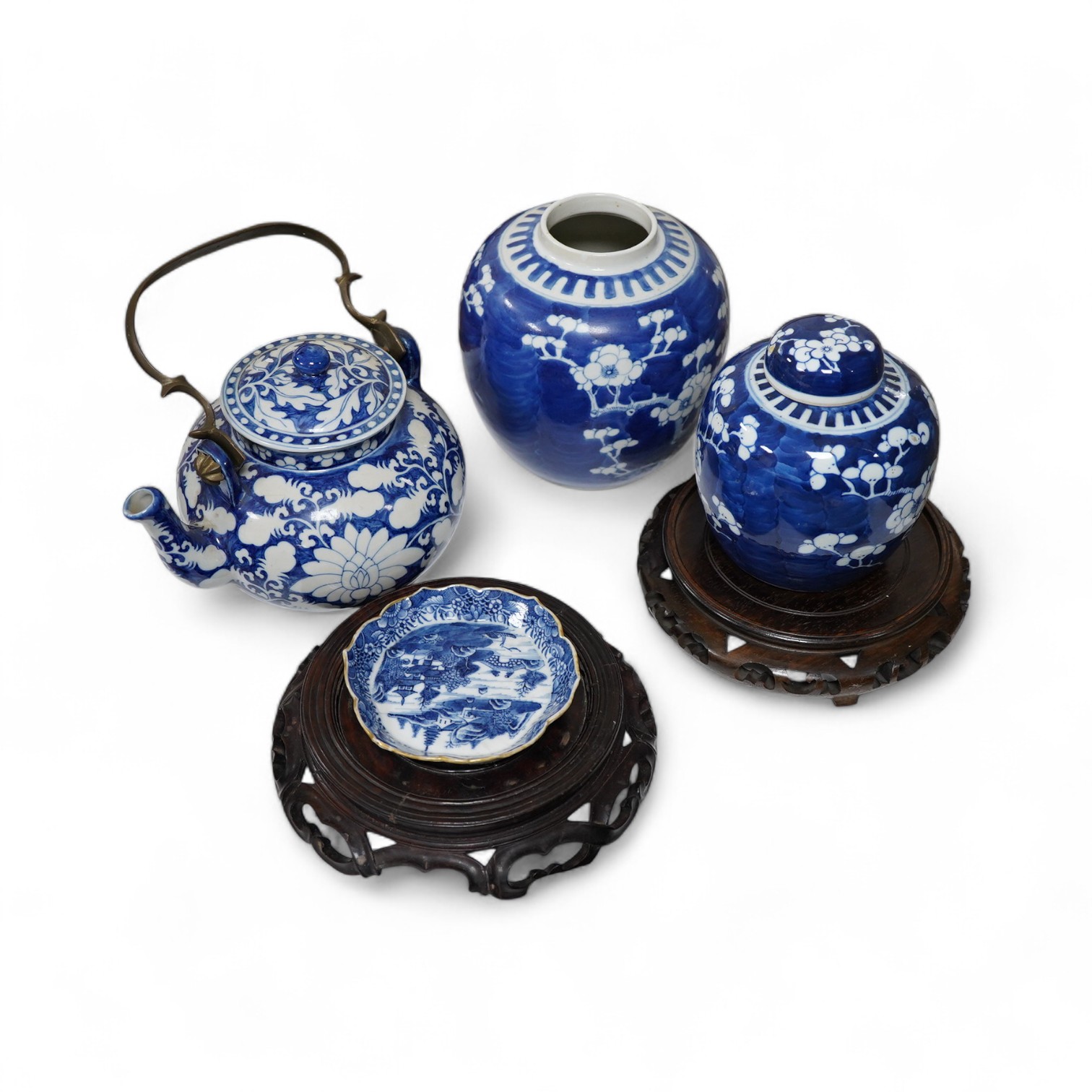 An 18th century Chinese blue and white dish, two jars (one without cover), a teapot and two carved wooden stands